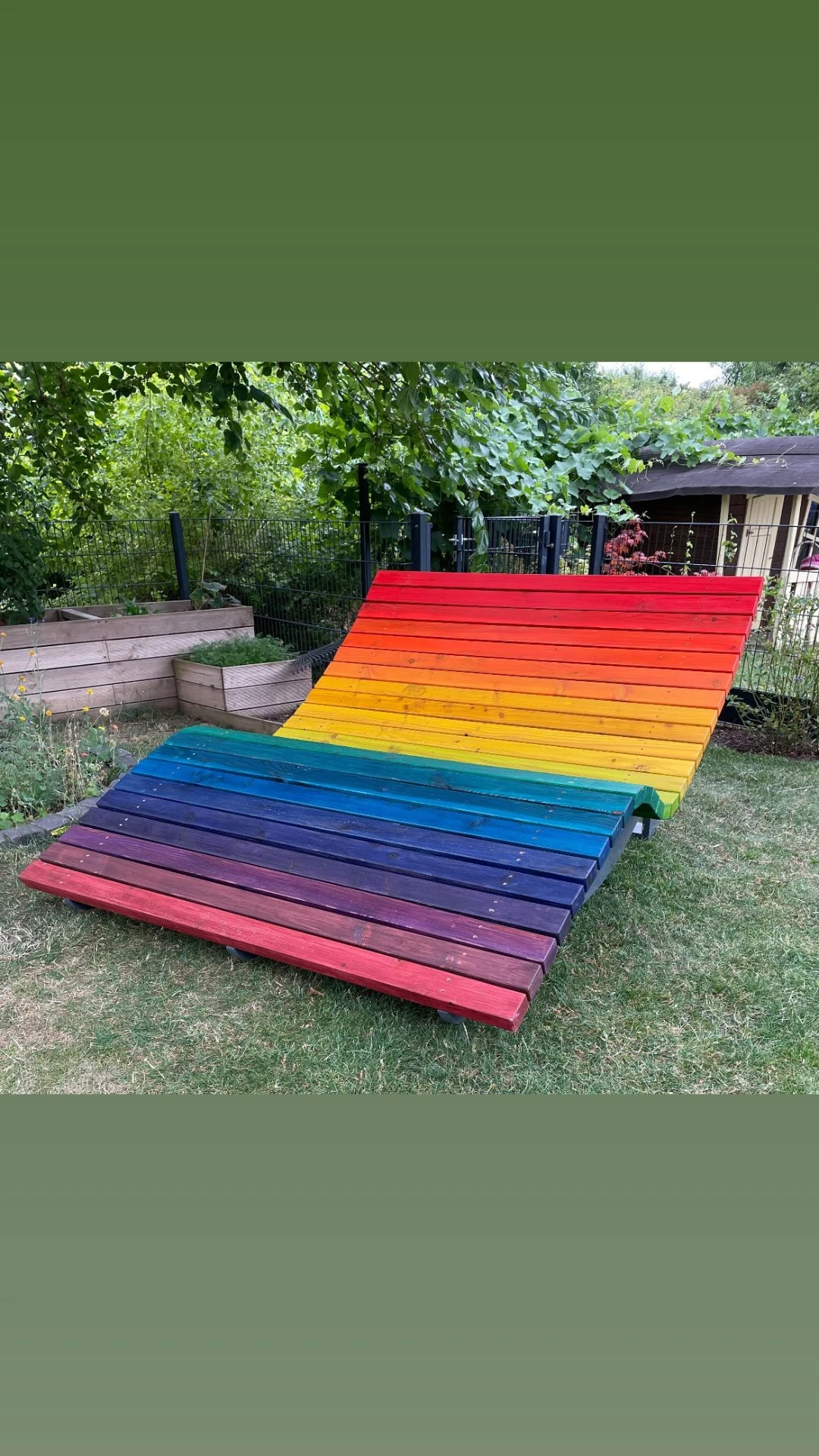 Selbst gebaute Gartenliege aus Holz, bunt lasiert in Regenbogenfarben